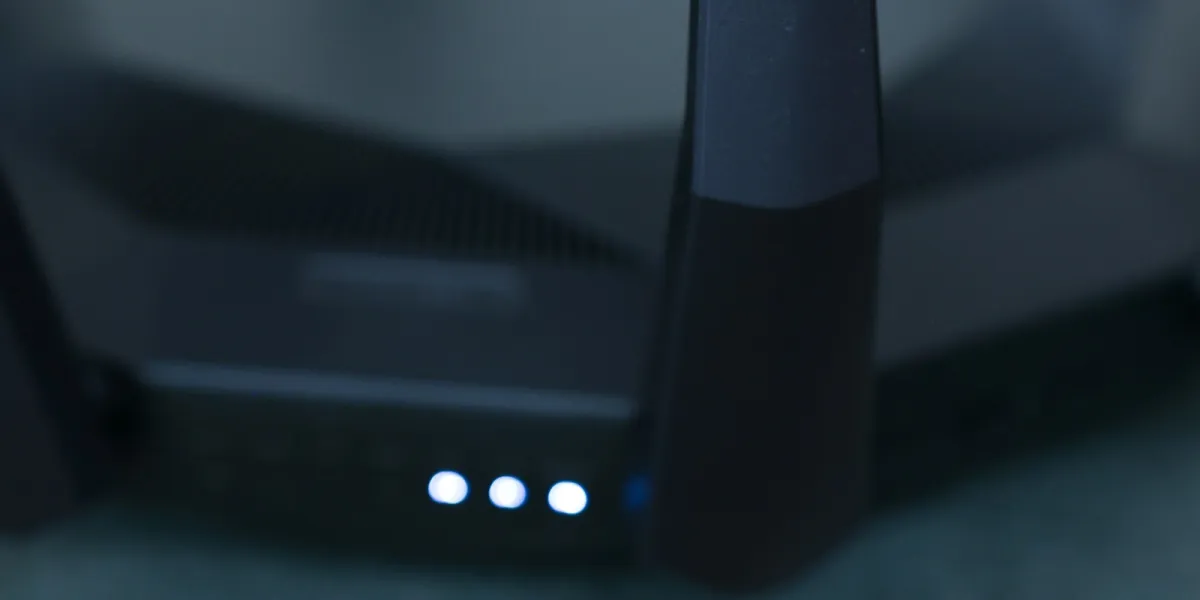 Close-up of a black wireless router's antennas with three blue status lights glowing Close-up of a black wireless router's antennas with three blue status lights glowing