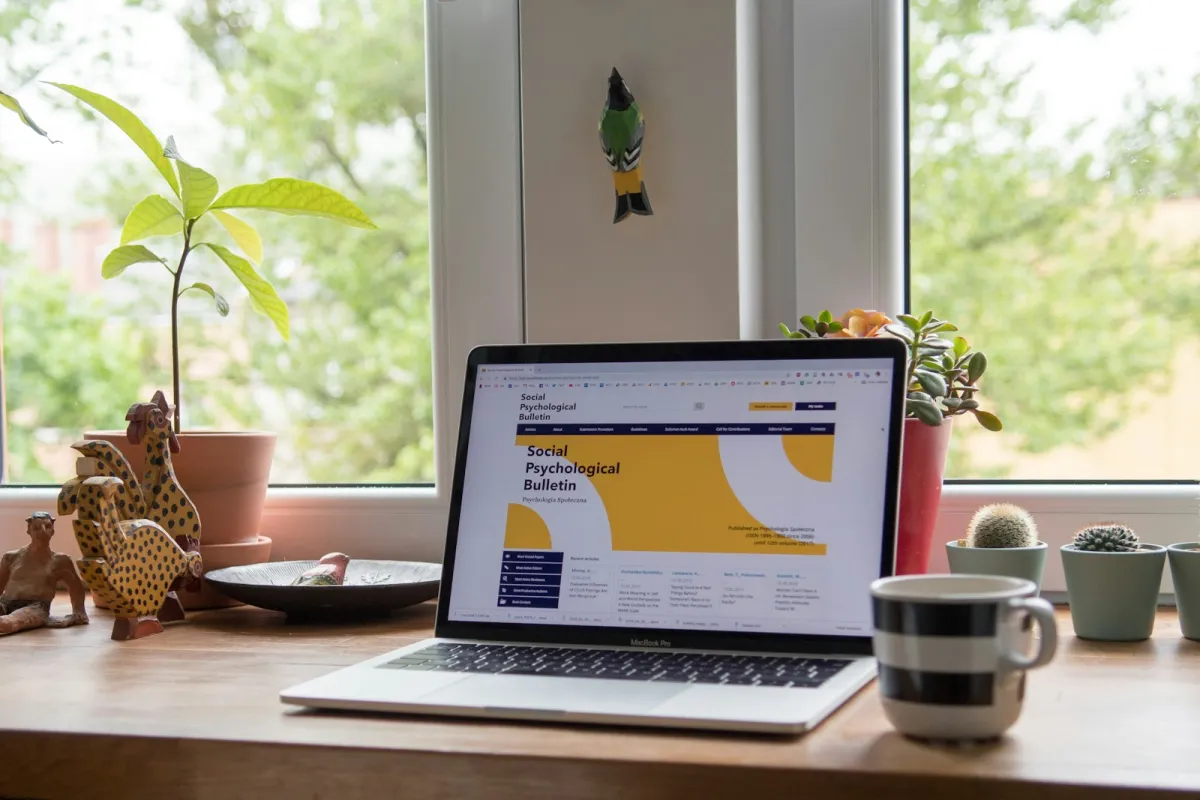 A laptop on a wooden desk by a window with potted plants A laptop on a wooden desk by a window with potted plants