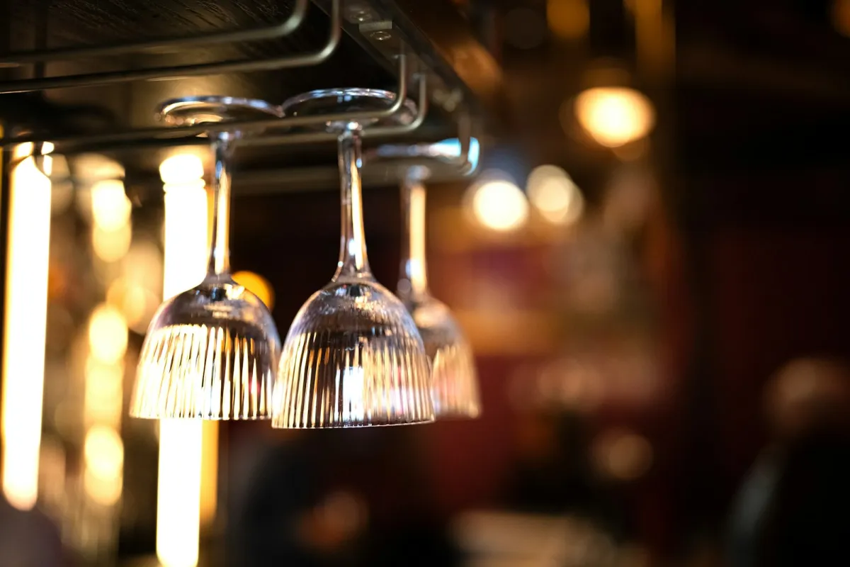 Empty wine glasses hanging upside down from a bar rack Empty wine glasses hanging upside down from a bar rack