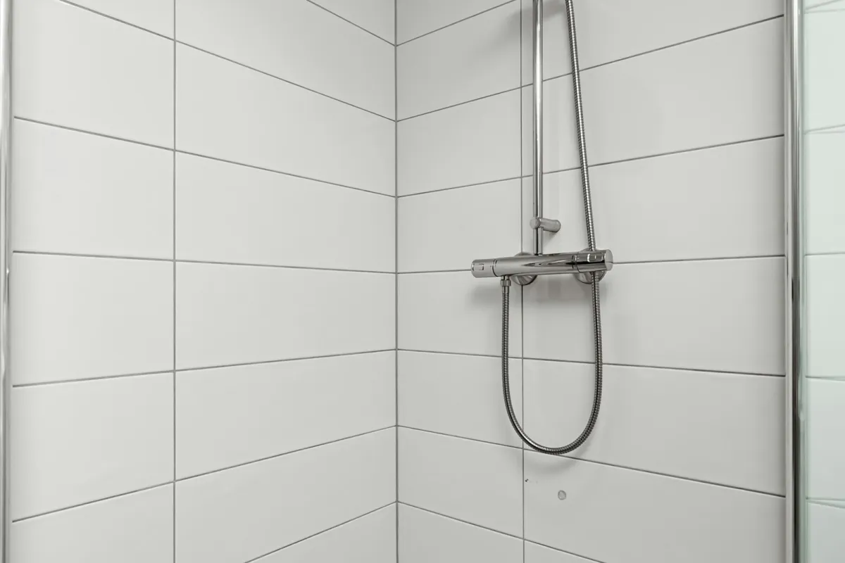A white tiled walk-in shower with a chrome shower rail A white tiled walk-in shower with a chrome shower rail
