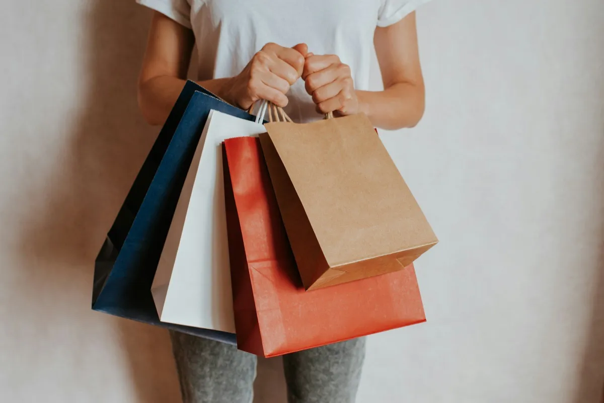 Person holding blue, white, red and brown paper shopping bags
