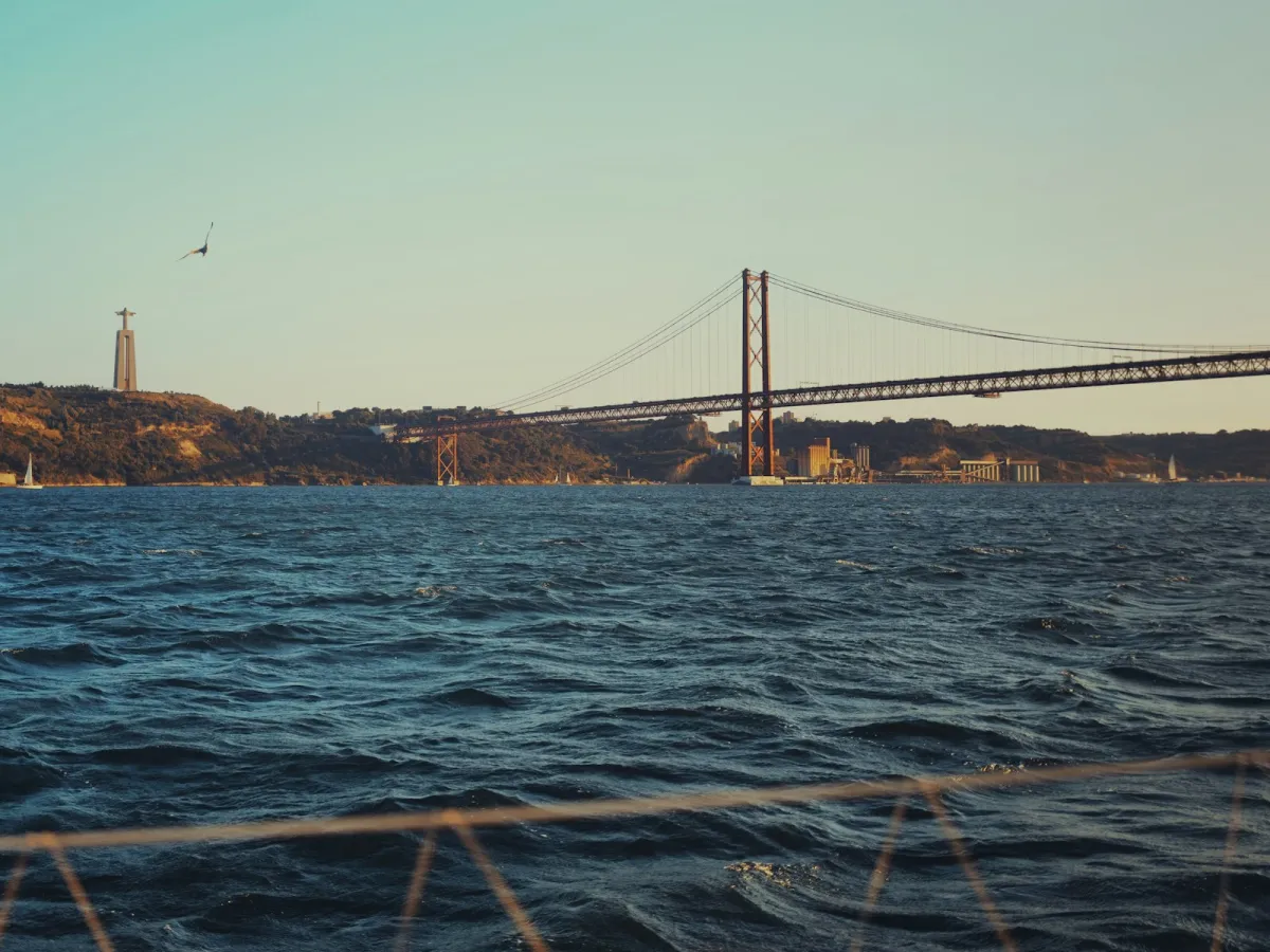 A bridge across the wide River Tagus in Lisbon with a monument in the distance