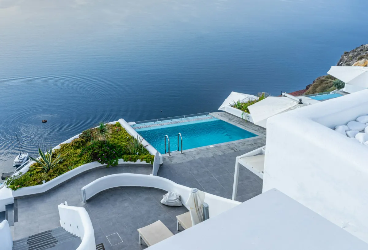 White-walled infinity pool overlooking the sea on a sunny day in Oia, Greece White-walled infinity pool overlooking the sea on a sunny day in Oia, Greece