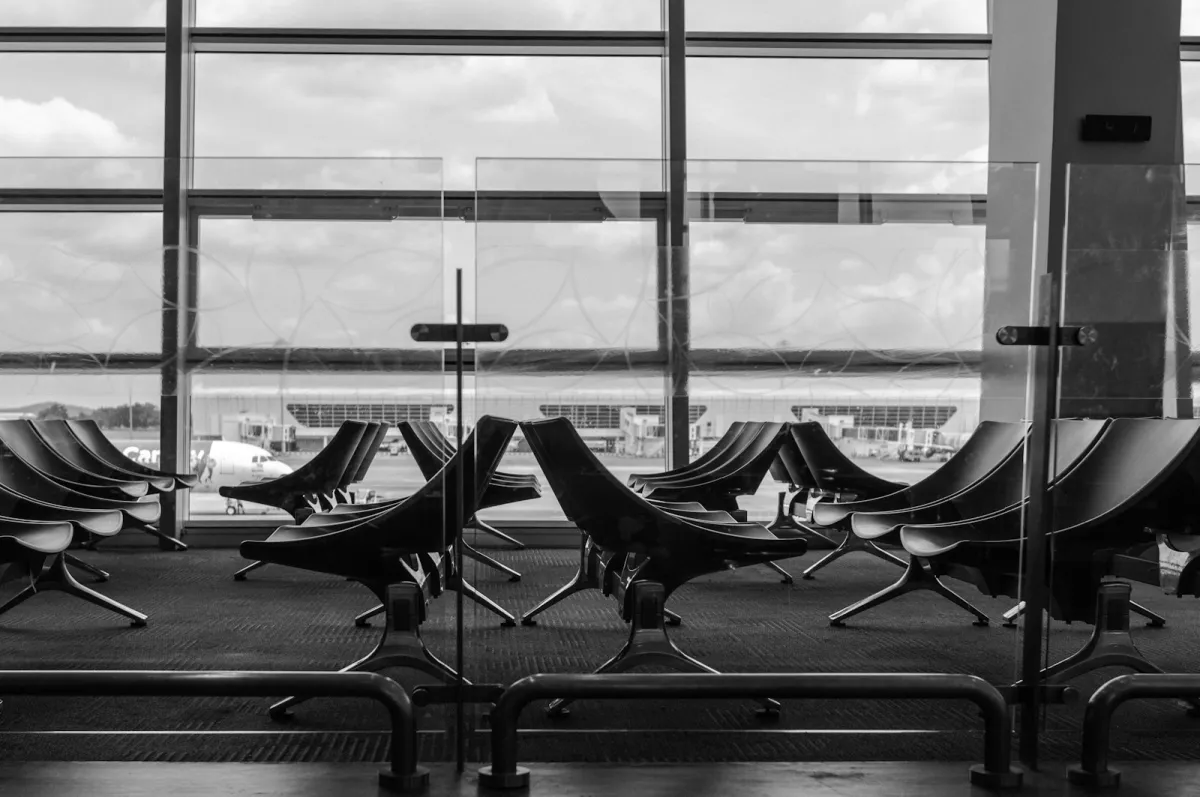 Empty airport departure seating in front of large windows overlooking the apron