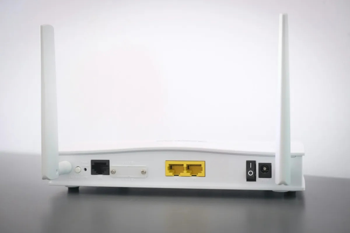 Back of a white wifi router with two aerials and its ports on a desk Back of a white wifi router with two aerials and its ports on a desk