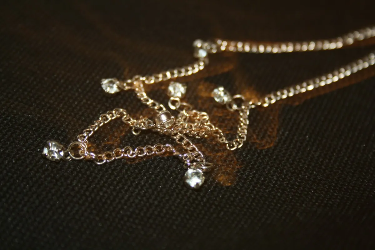 Fine chain necklace with clear stones on dark fabric