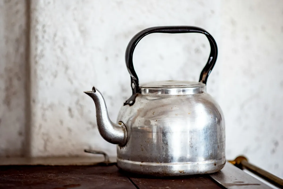 Stainless steel kettle with a black handle on a wooden surface