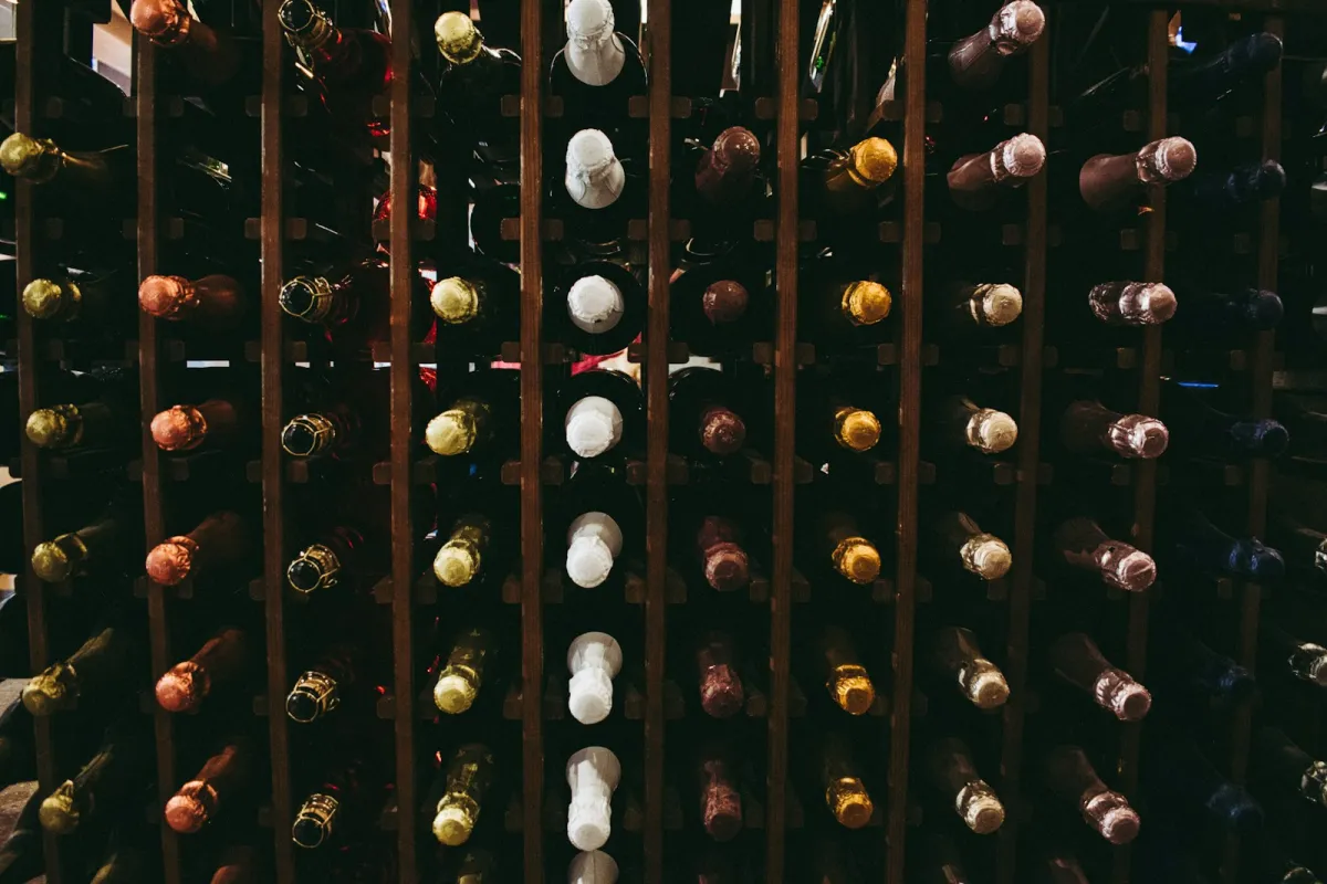 Rows of wine and sparkling wine bottles stored in a wooden rack Rows of wine and sparkling wine bottles stored in a wooden rack