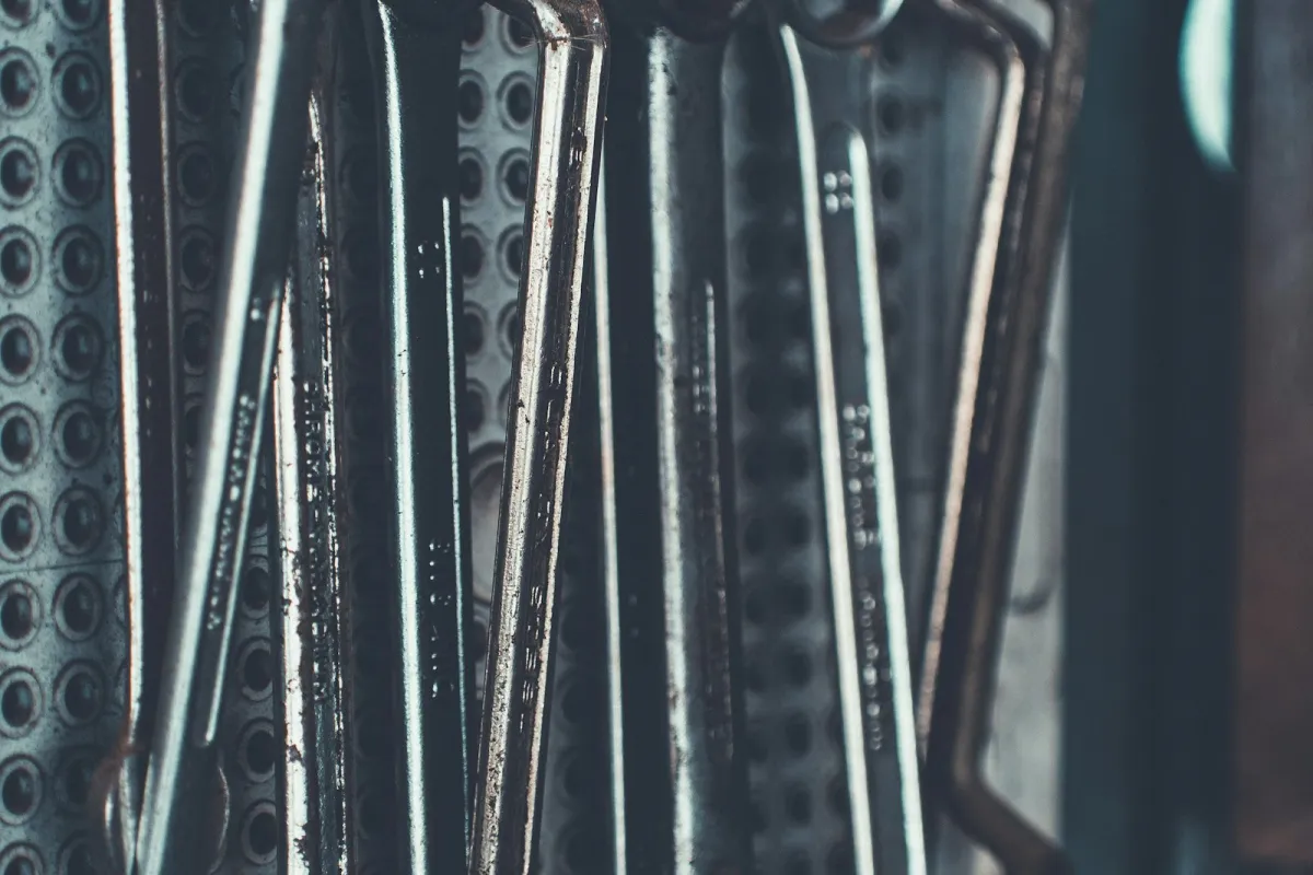 A row of well-used combination spanners hanging on a pegboard in a workshop