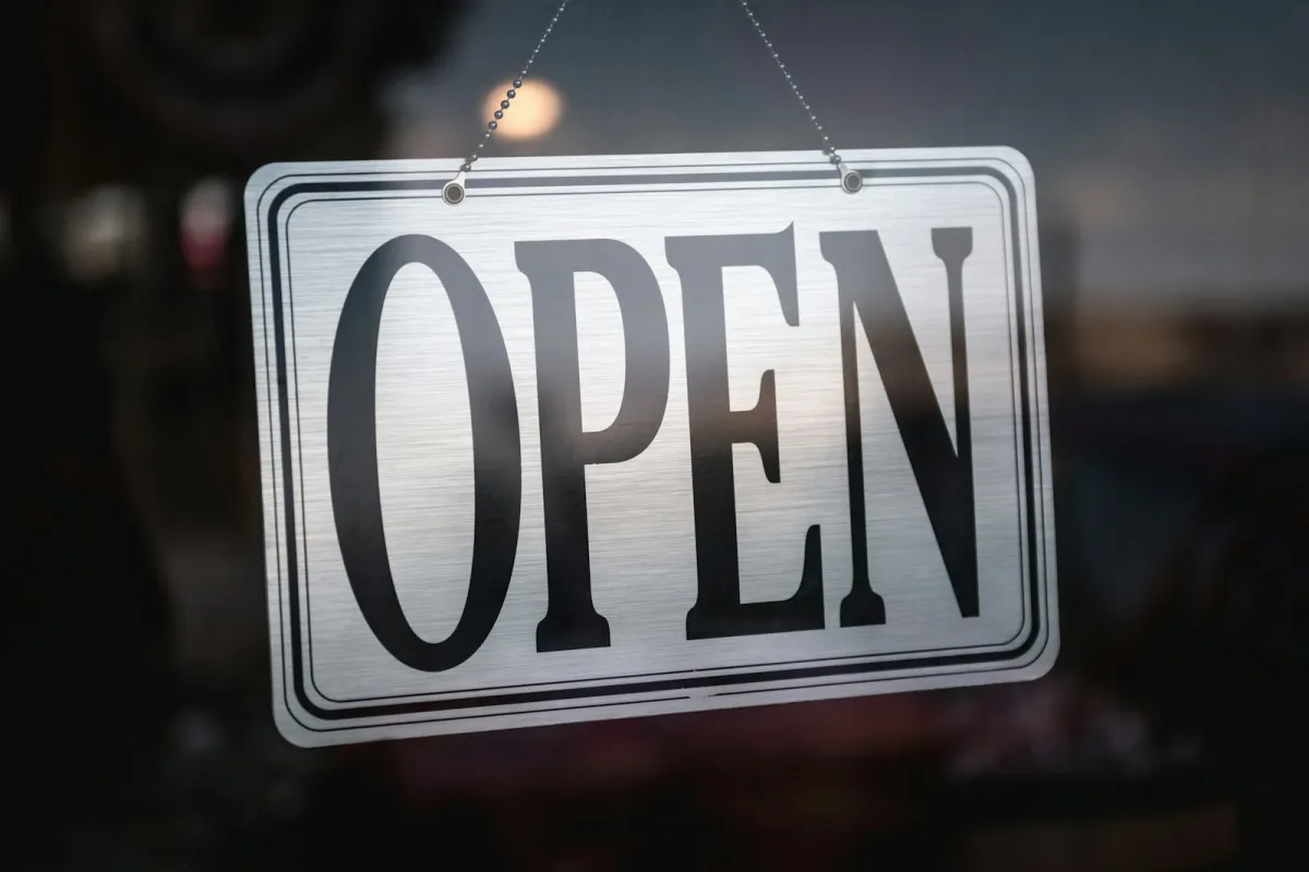 A metal Open sign hanging in a shop door A metal Open sign hanging in a shop door