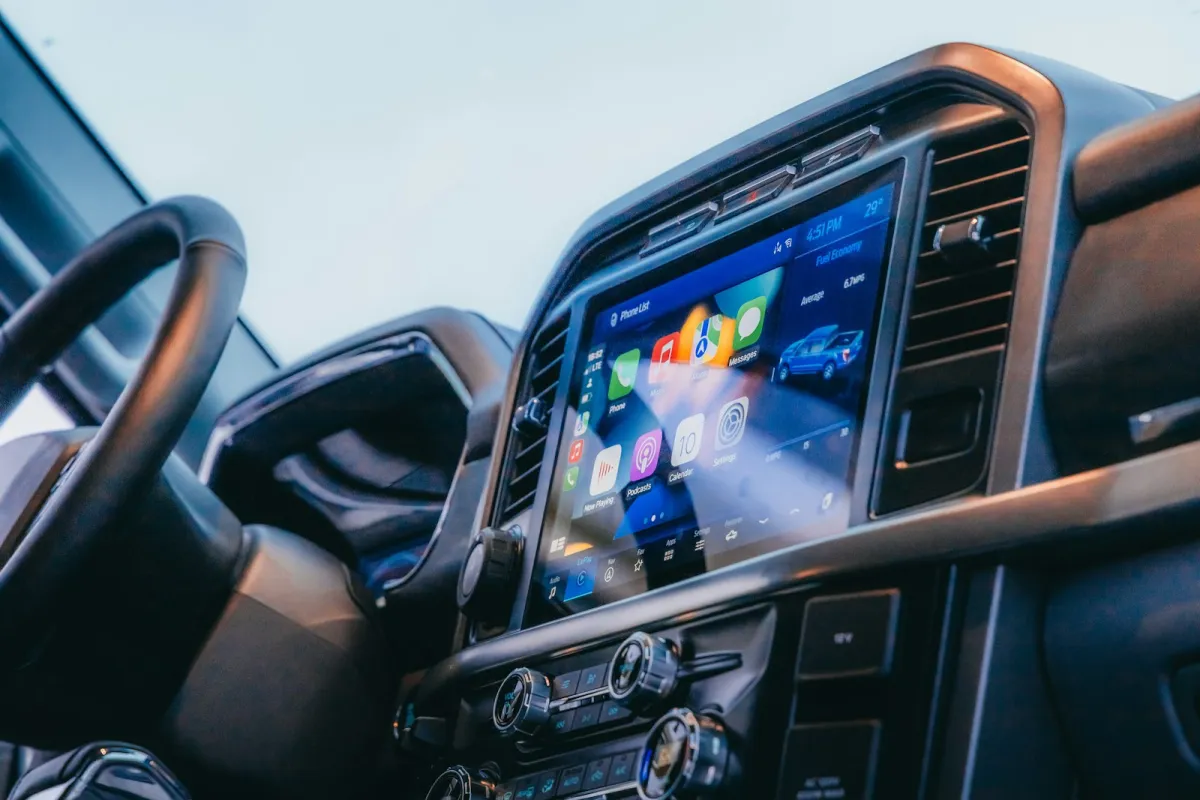 A large dashboard touchscreen showing phone apps beside the steering wheel of a car A large dashboard touchscreen showing phone apps beside the steering wheel of a car