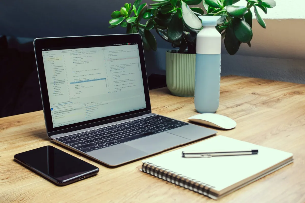 Laptop, phone, notebook and a reusable bottle on a wooden desk Laptop, phone, notebook and a reusable bottle on a wooden desk