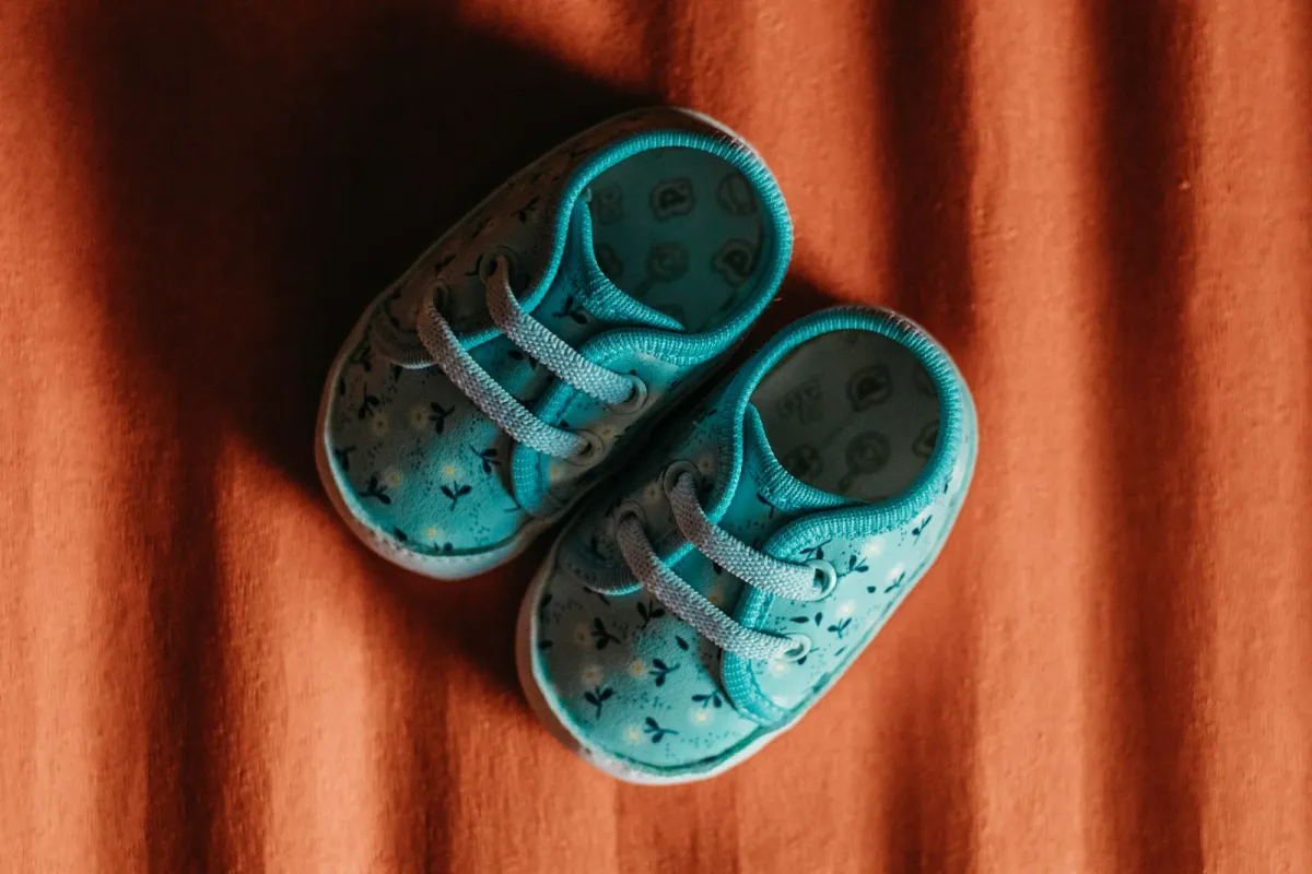 A pair of small blue patterned children's shoes on an orange blanket