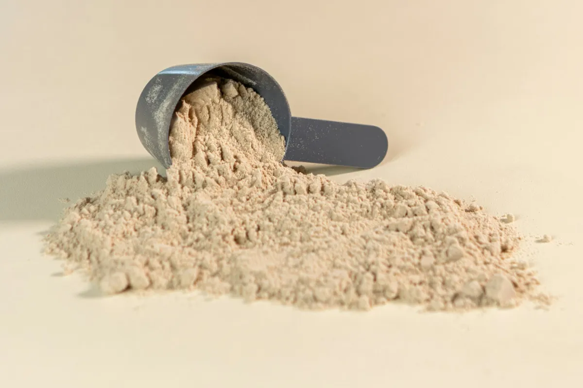 Scoop of protein powder spilling onto a table