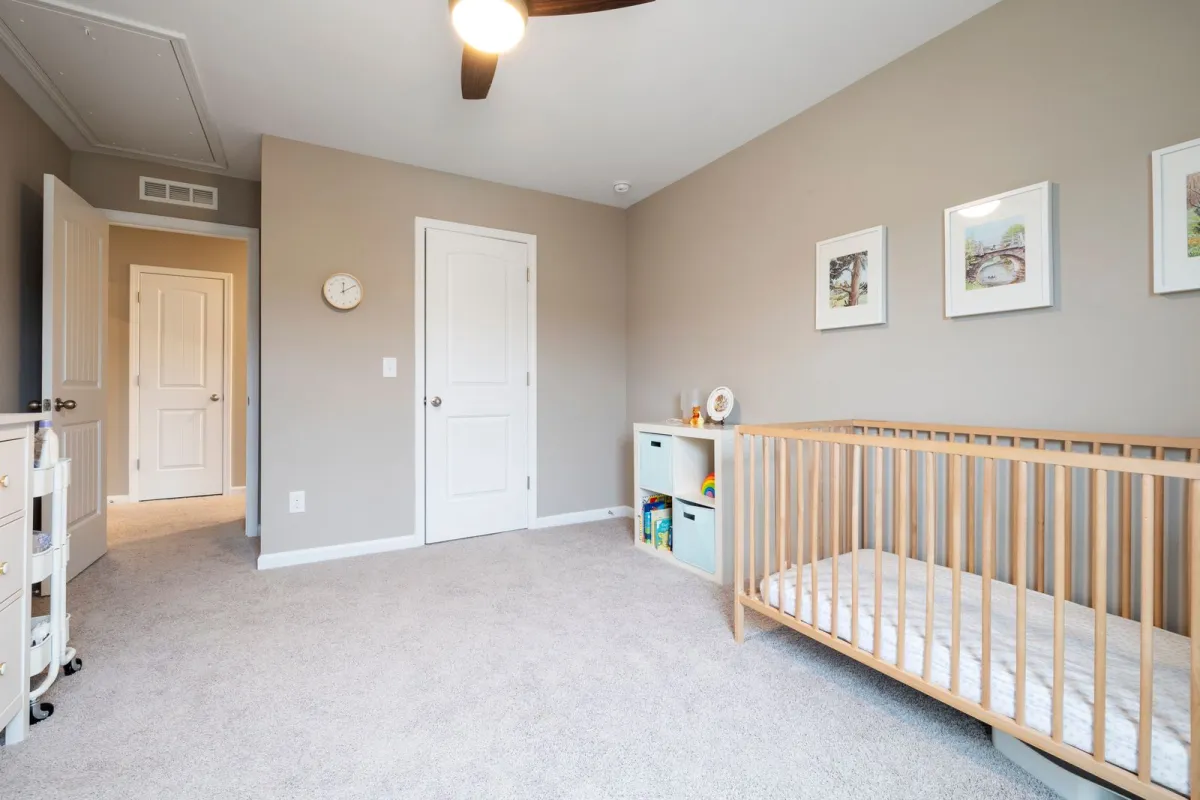 A calm nursery with a wooden cot, storage cubes and framed prints on the wall