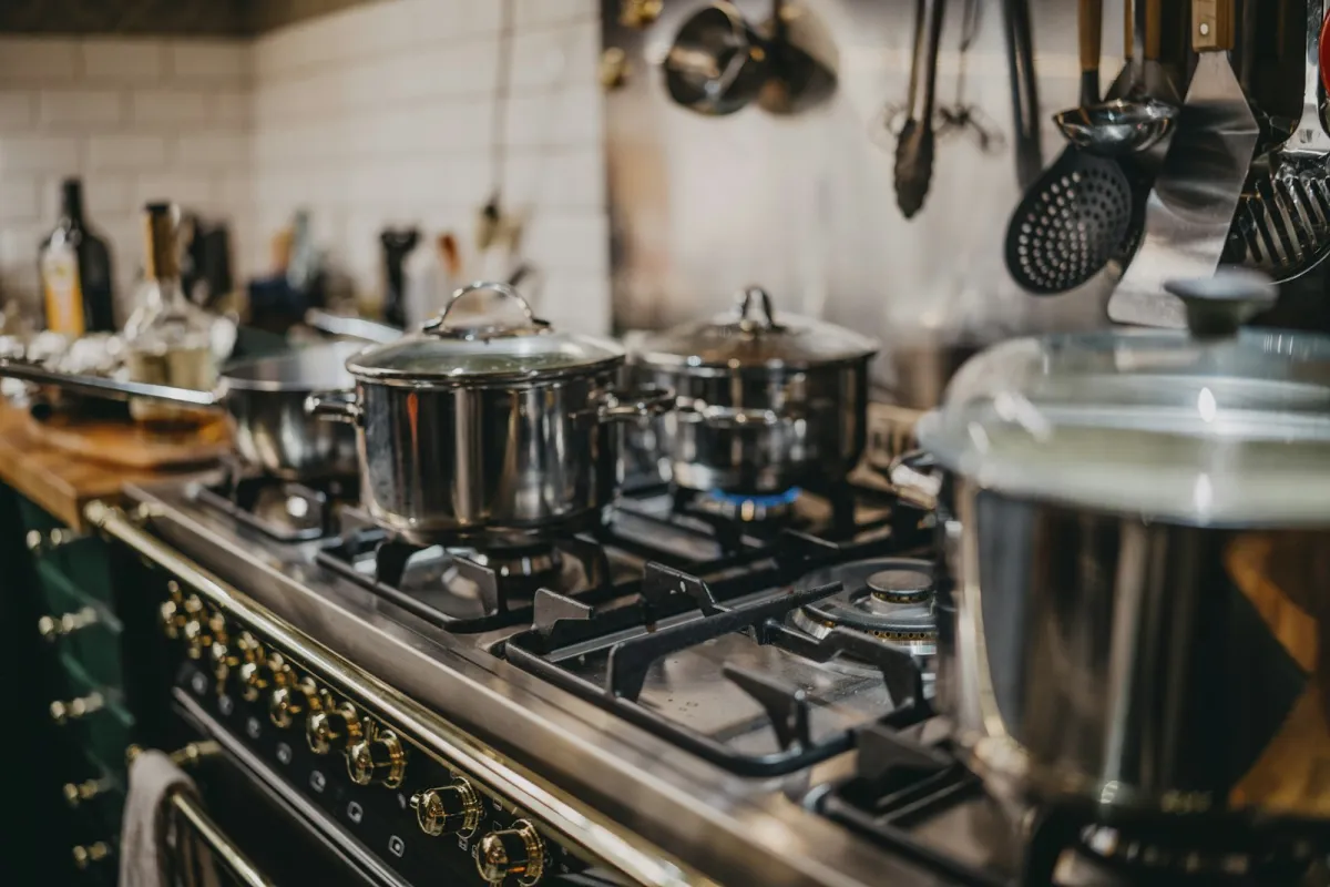 Stainless steel pans with glass lids on a gas range cooker Stainless steel pans with glass lids on a gas range cooker