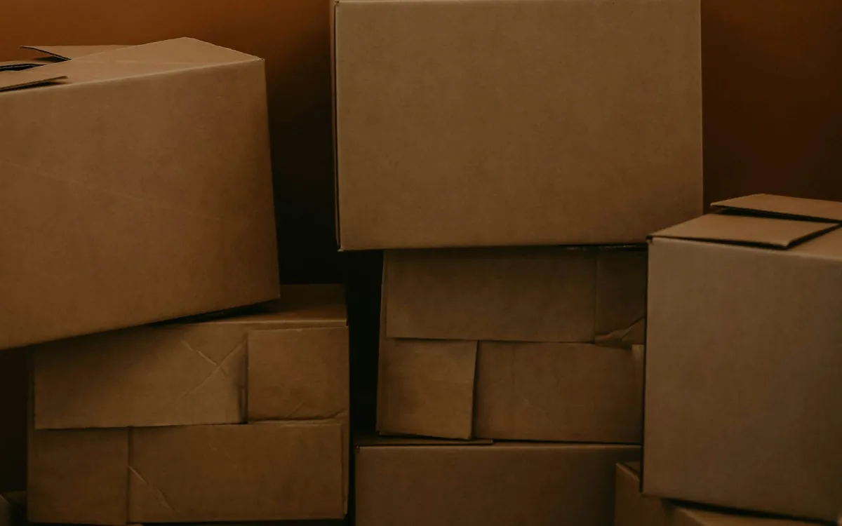 Stacked plain cardboard boxes against a brown wall