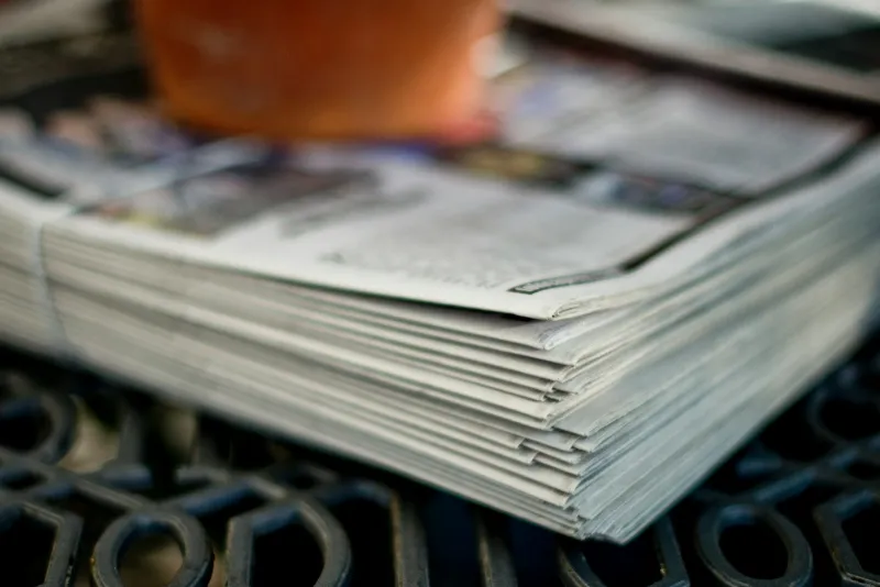 A stack of folded newspapers on a metal table