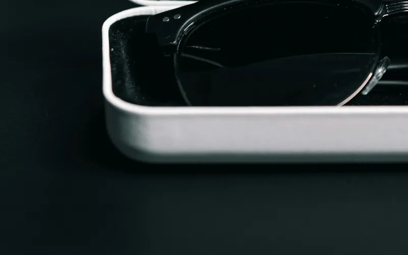 A pair of dark-framed glasses resting in an open white glasses case