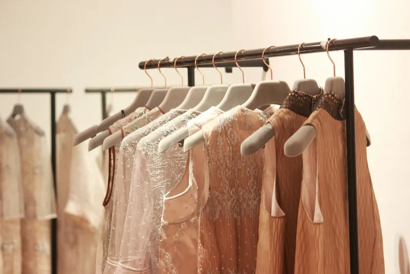 Pale dresses and tops on velvet hangers along a clothes rail