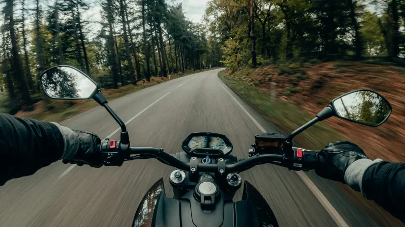 ASMAX: helmet intercoms and tyre inflators for riders Rider's view over motorcycle handlebars on a tree-lined country road