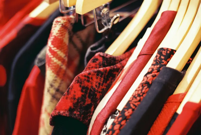 Red and black patterned dresses on wooden hangers along a clothing rail