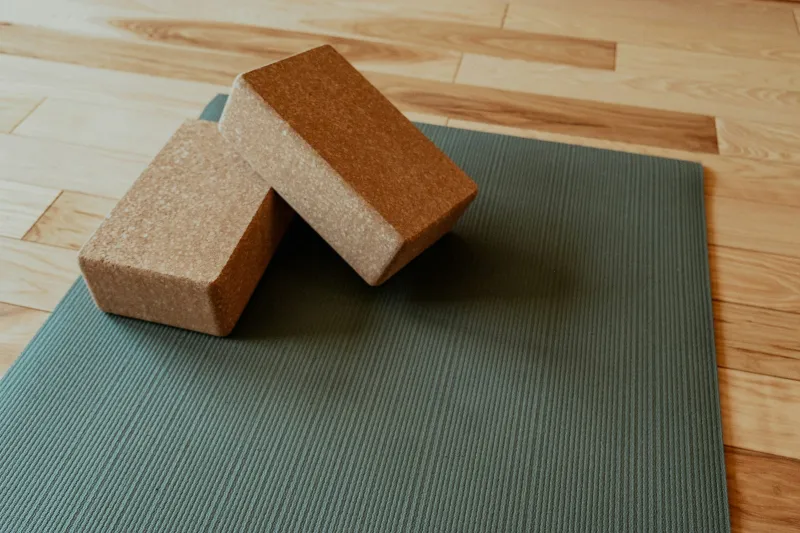 Green yoga mat with two cork blocks on a wooden floor