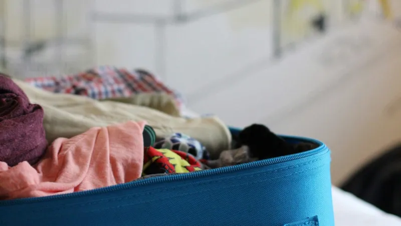Blue soft suitcase packed with folded clothes