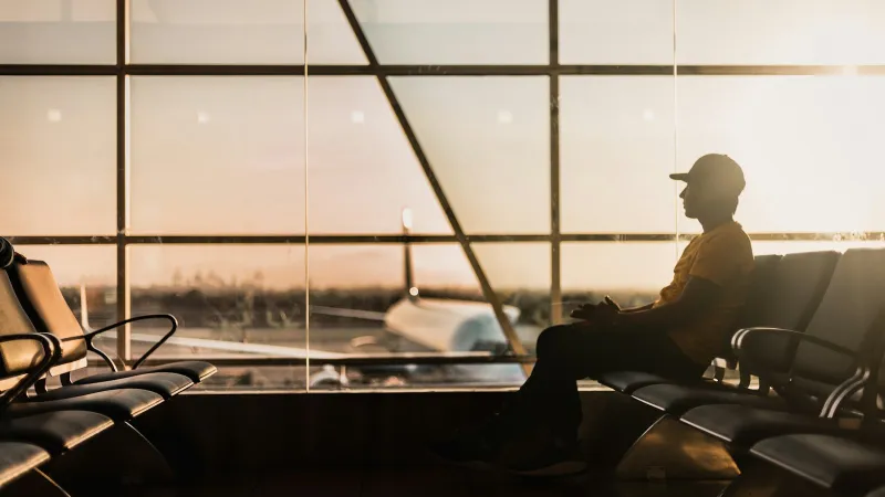 Silhouette of a traveller waiting by a large airport window with a plane outside