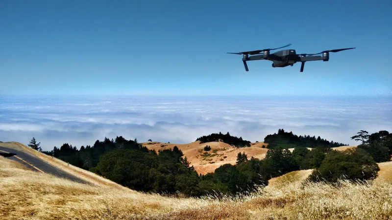 A camera drone flying over golden hills above a sea of cloud