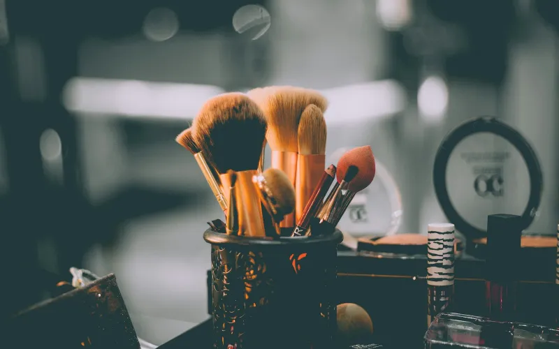 Makeup brushes and a beauty sponge in a pot on a dressing table