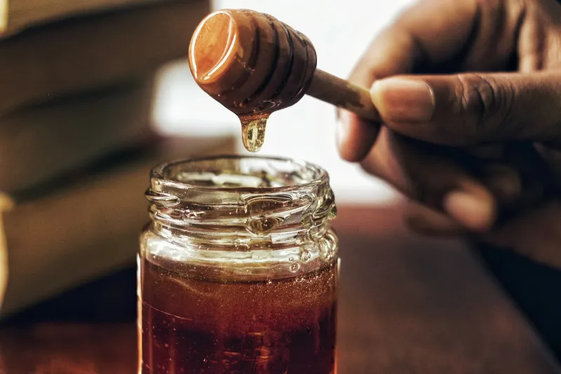 BioBees: royal jelly vials, capsules and jars from a small UK shop Honey dripping from a wooden dipper into a glass jar