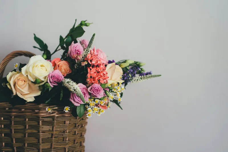 Bouquet of roses and mixed flowers in a wicker basket