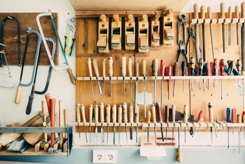 Hand tools, chisels and saws hanging on a workshop wall rack