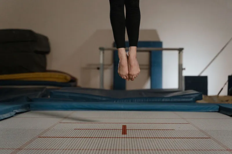 Bare feet mid-bounce above an indoor trampoline