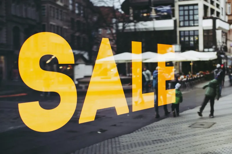 Large yellow SALE lettering on a shop window overlooking a winter shopping street
