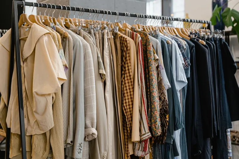 A long rail of shirts, jackets and knitwear on wooden hangers in a clothing shop