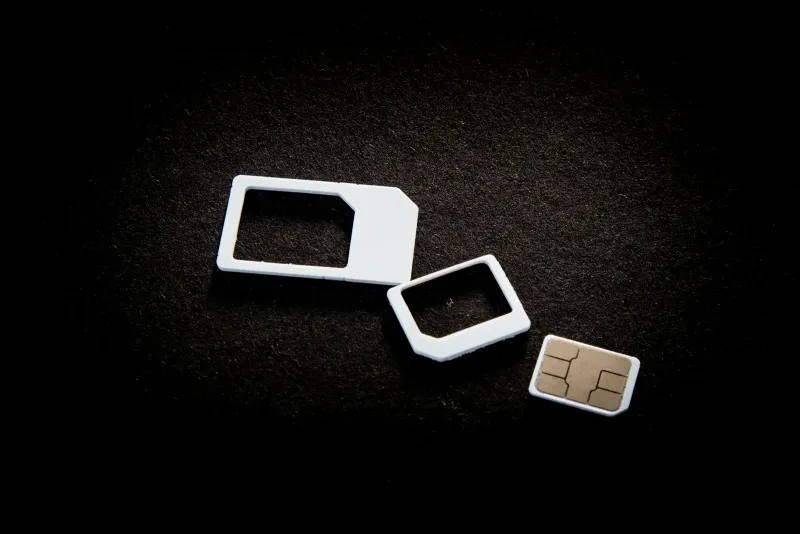 A SIM card and two SIM adaptors on a dark background
