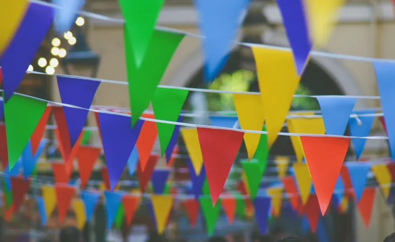 British Made Gifts: personalised banners, Mini Mes and more, made in Yorkshire Strings of colourful pennant bunting hanging against a white sky