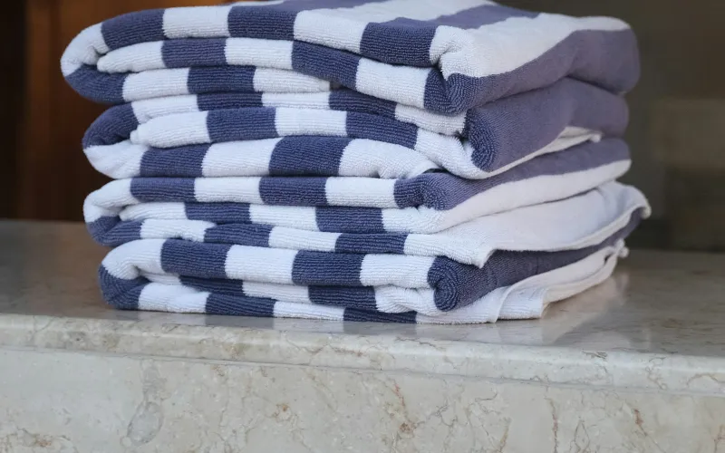 A stack of folded blue and white striped towels on a marble counter