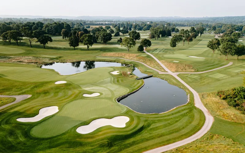 Aerial view of a golf course with greens, bunkers and a lake