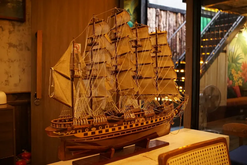 A detailed wooden model of a tall ship with many sails on a display stand