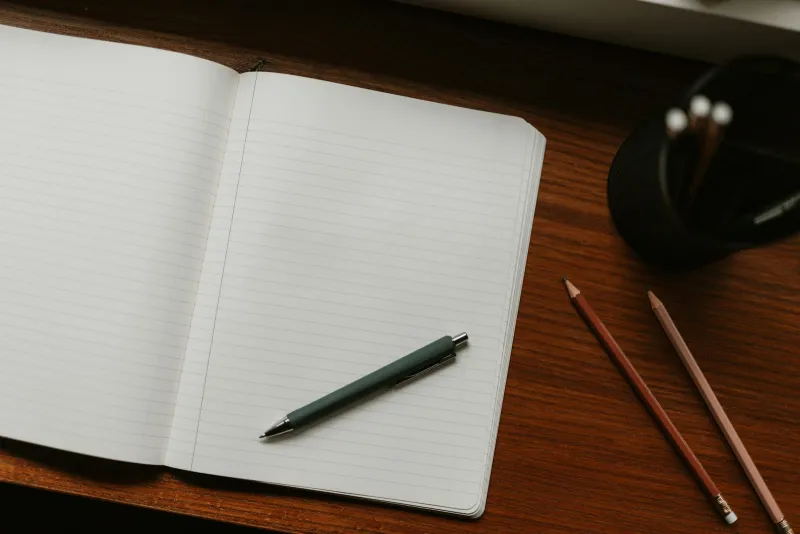 CloudLearn: online GCSE and A-Level courses you can study at your own pace An open lined notebook with a pen on a wooden desk beside two pencils