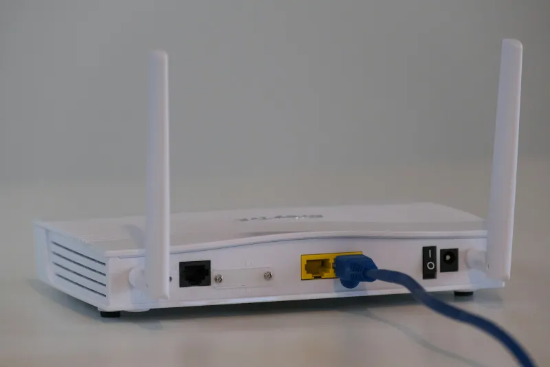 The back of a white broadband router with a blue network cable plugged in