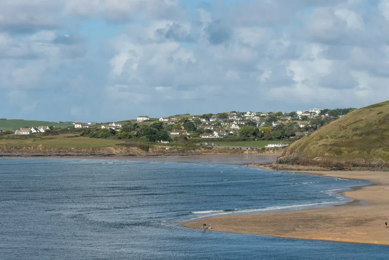 A sandy bay and coastal village under a cloudy sky on the British coast