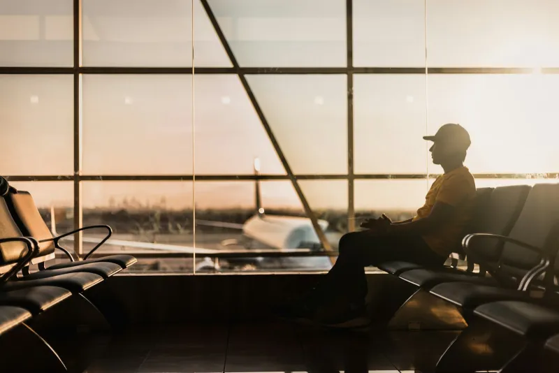 Silhouette of a traveller waiting in an airport departure lounge at sunset