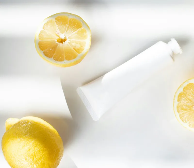 Unbranded white cream tube beside halved lemons