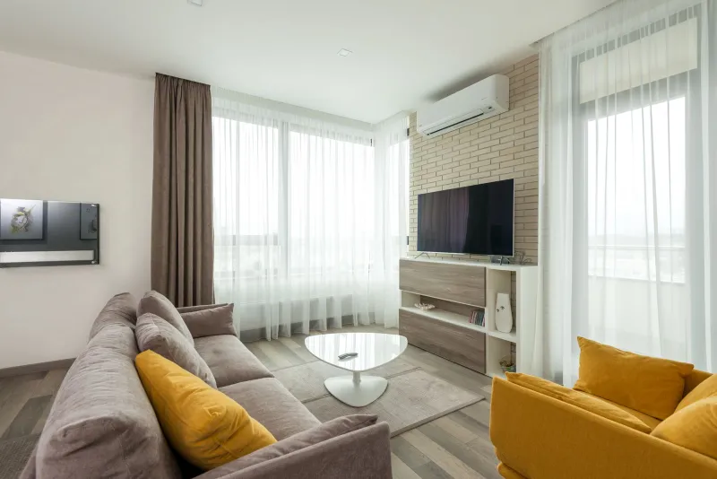 Bright modern living room with a flat-screen TV, grey sofa and mustard armchair