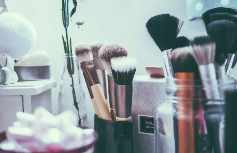 Assorted make-up brushes standing in jars on a dressing table