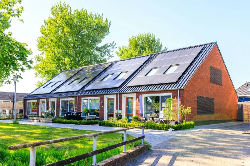 Row of red-brick terraced houses with solar panels covering the roof